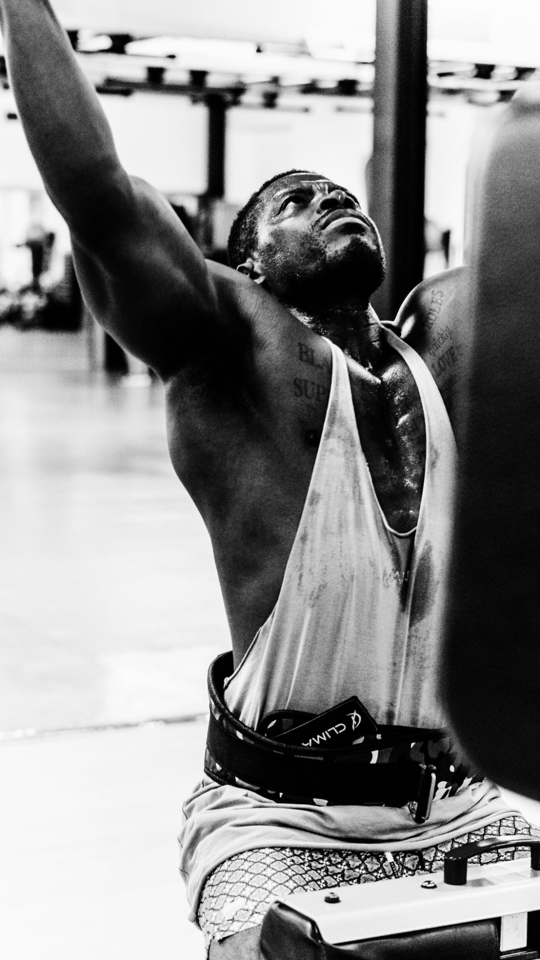 Black-and-white shot of a lifter mid-set, arms raised at the gym